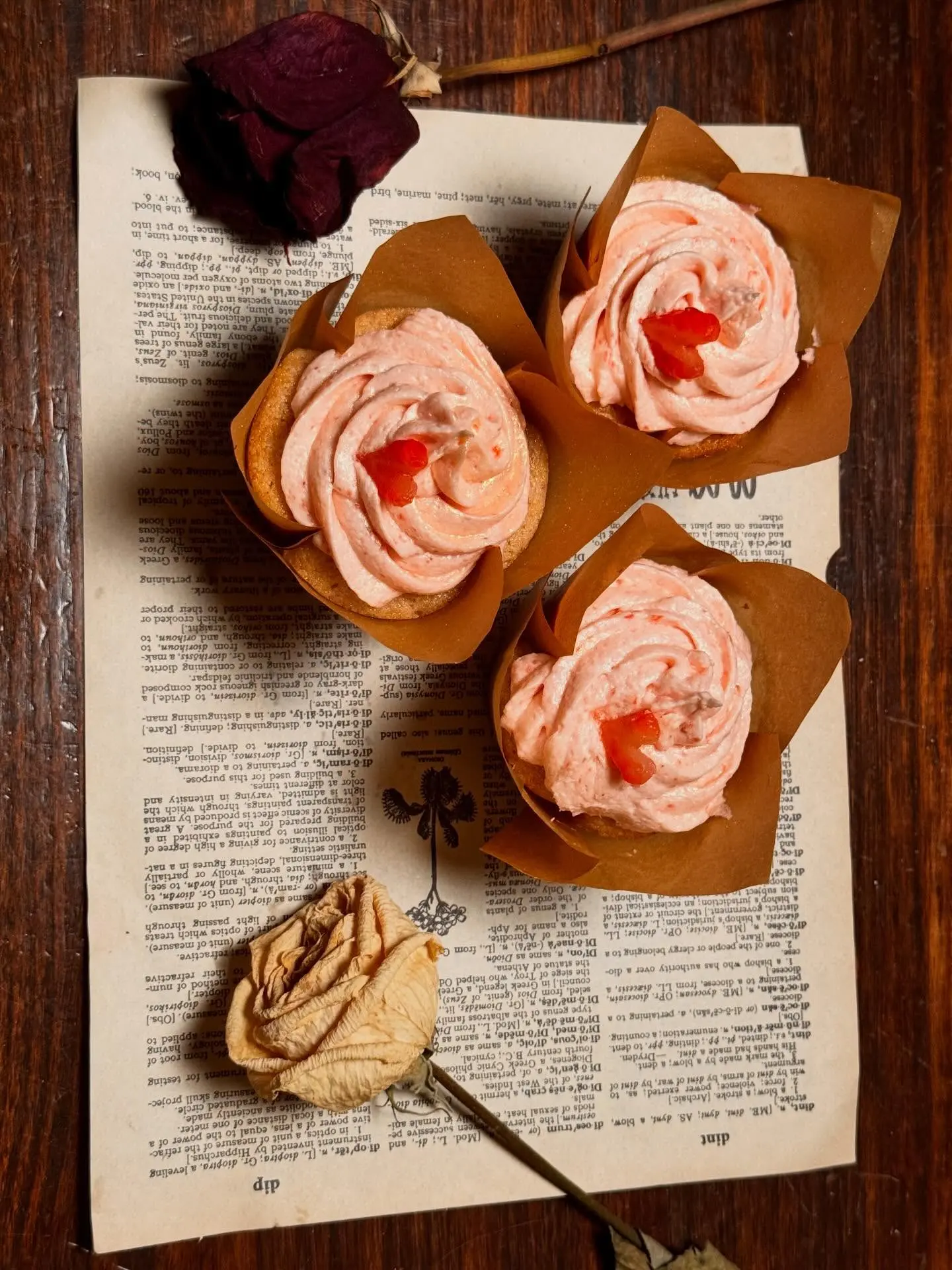 Strawberry cupcakes styled with dried roses on a vintage book page