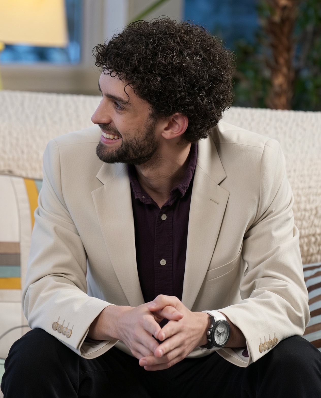 A seated man smiling during a relaxed studio portrait session